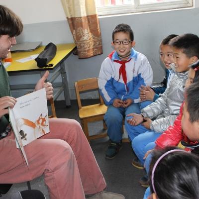A Projects Abroad volunteer teaching English by reading to the children in China A volunteer reads a book to his students during his teaching work experience in China